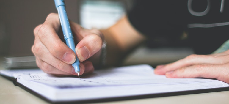 A man writing in the notebook.