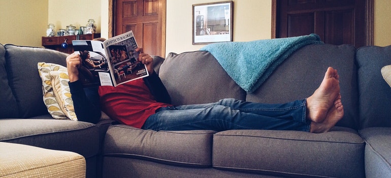 A person reading a magazine on the couch.