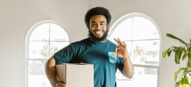 a mover holding a box and smiling