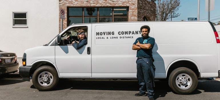 Two workers from top movers in Milwaukee with their white van on a sunny day.
