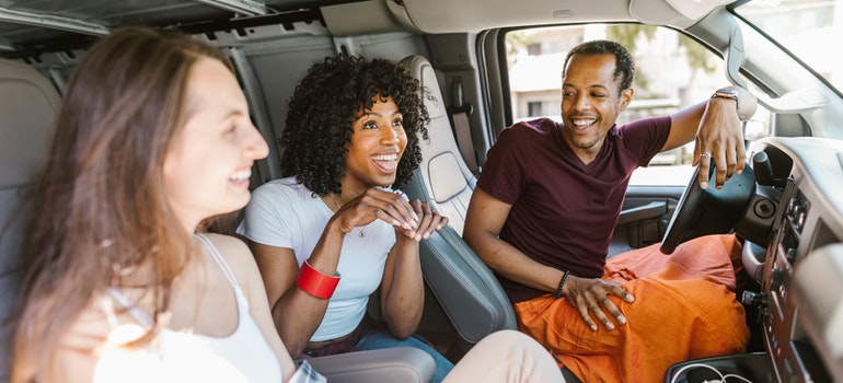 Three people sitting in a van and laughing.