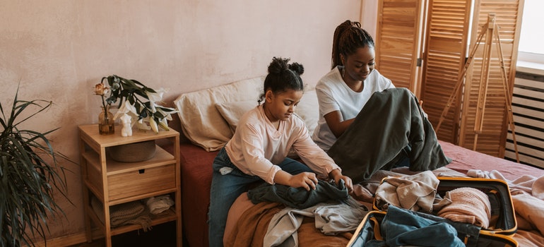 A mother and her daughter folding clothes.