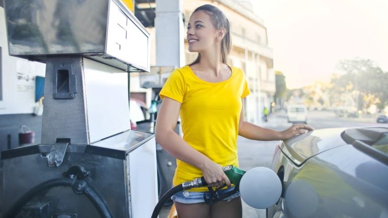 A woman pumping gas.