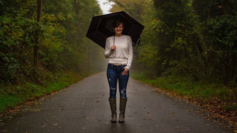 A woman standing in the rain and holding an umbrella.
