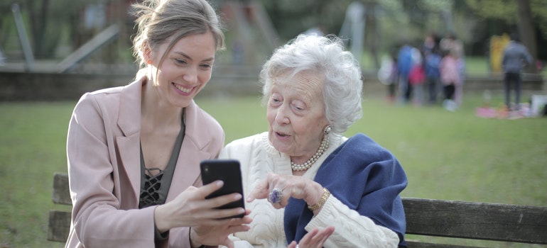 A woman showing something on her phone to an elderly woman.