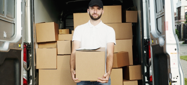 A man holding boxes in front of a moving van