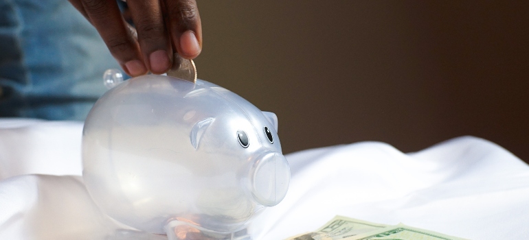 A person putting a coin in piggy bank.