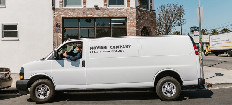 A man who's working for top movers in Long Beach sitting in their white van.