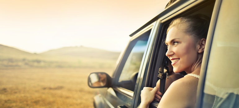 A woman looking through a car window and smiling.