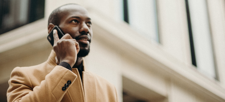 A man in a brown coat making a phone call.
