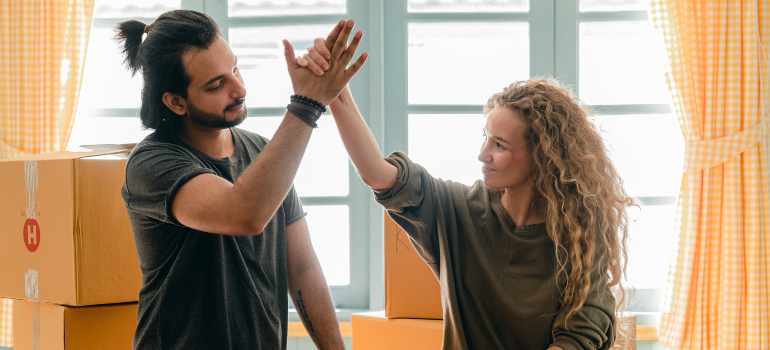 A man and a woman sharing a high five after hiring cross country moving companies Georgia.