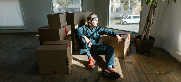 A worker from cross country moving companies Georgia sitting between several carton boxes.