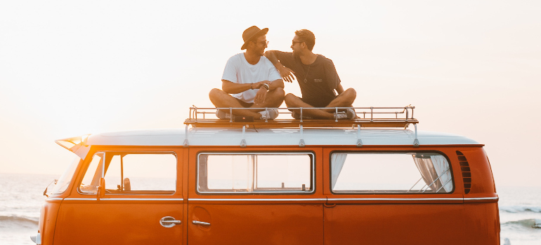Two men sitting on an orange van and talking.