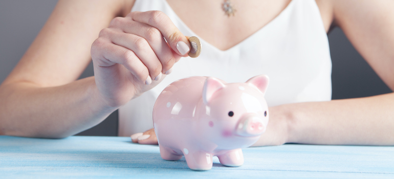 A woman putting a coin in her piggy bank.