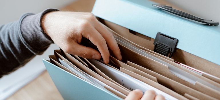 person packing documents in the folder as an example of what to do before you update license and registration when you move
