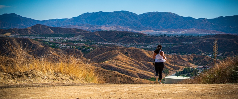 a woman running on a track, with Santa Clarita behind her