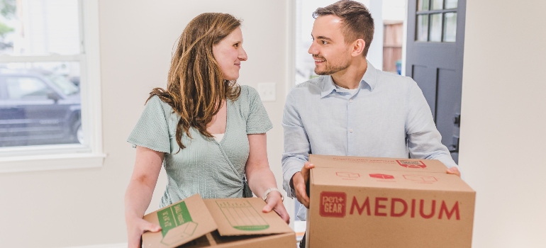 a couple carrying boxes before moving with long distance moving companies Palm Bay has to offer