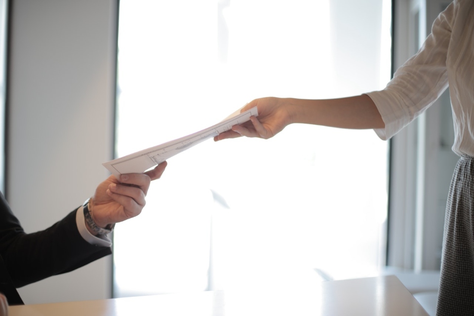 a person handing documents to another person