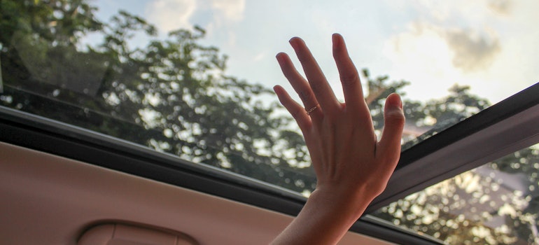 A person touching glass in the car.
