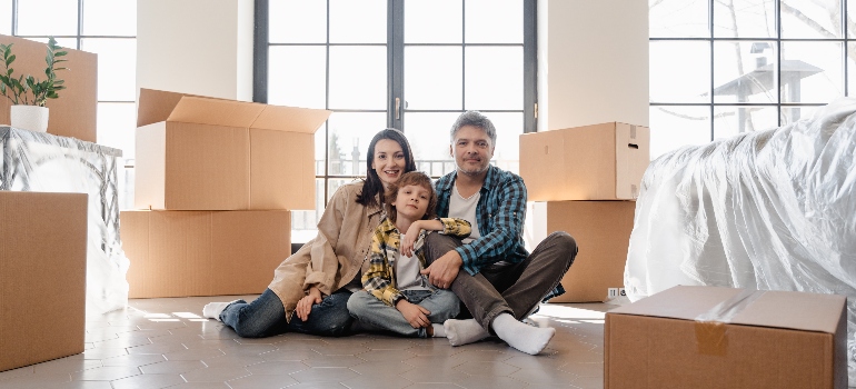 a family sitting in front of the moving boxes 