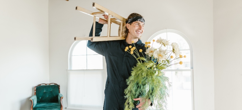 a man working for cross country moving companies McLean holding flowers and a stool