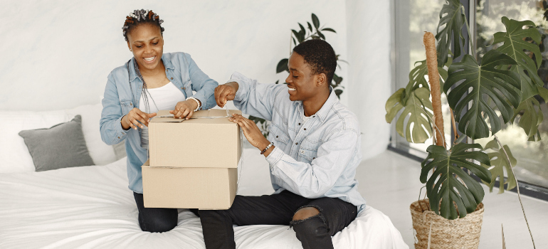 A couple packing a box on the bed and smiling.