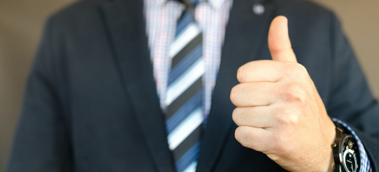 A person in a suit holding his thumb up