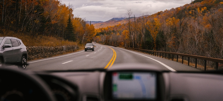A car driving on the road through autumn landscape.