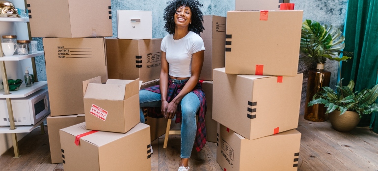 woman sitting next to a pile of boxes and smiling