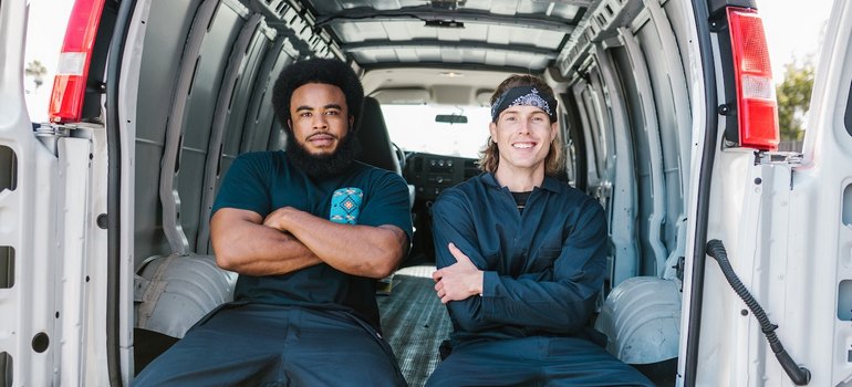 2 workers moving from massachusetts to ohio sitting in a van and smiling