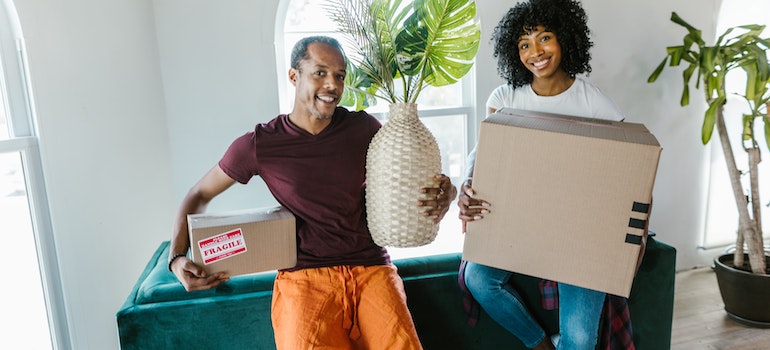 Two people holding boxes and smiling.