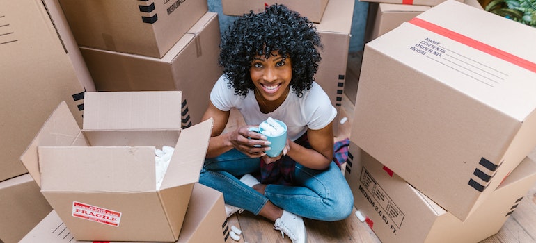 A woman smiling while sitting between many carton boxes.