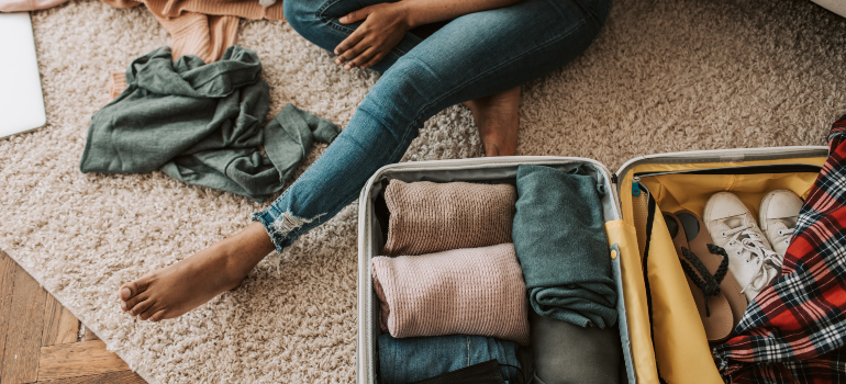 A woman packing her suitcase before moving from Florida to Utah.