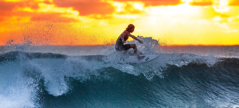 skilled man surfing during sunset