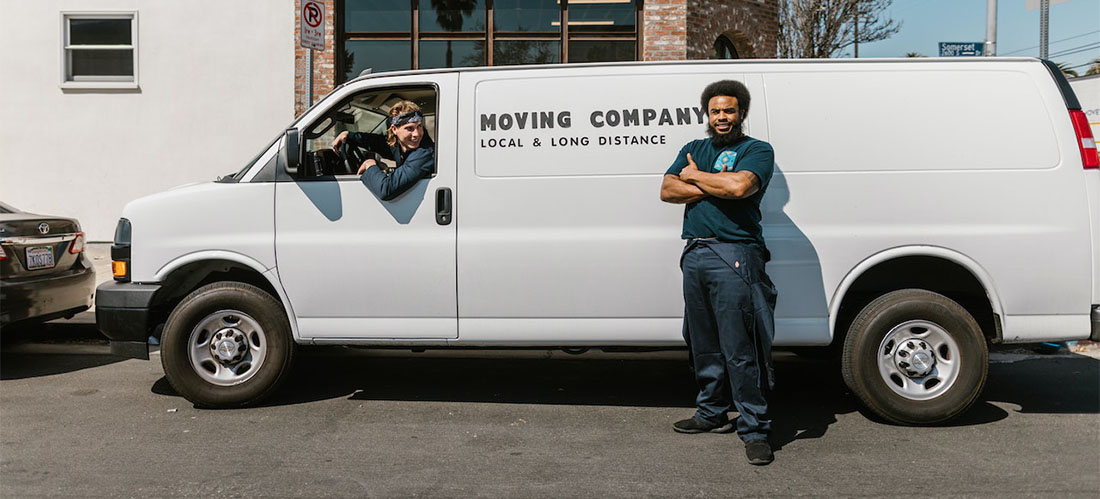 Two men working for long distance moving companies DC posing for a photo with their van.