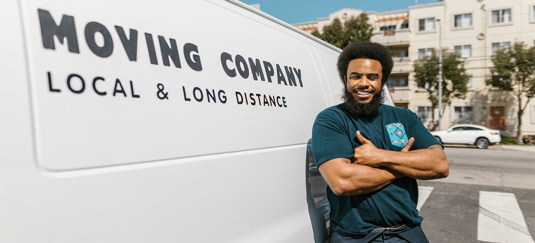 A worker from long distance moving companies Connecticut smiling next to a van.