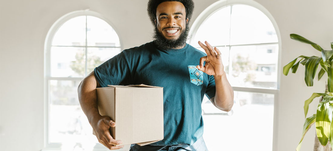 A worker from long distance moving companies Louisiana smiling while holding a box.