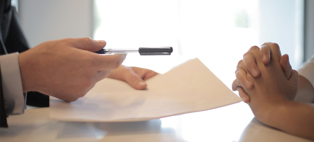 A man handing a pen to another person over a contract