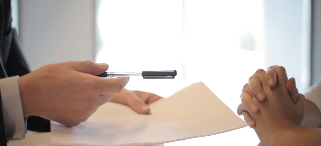 A person giving a pen to another person in order to sign a contract.