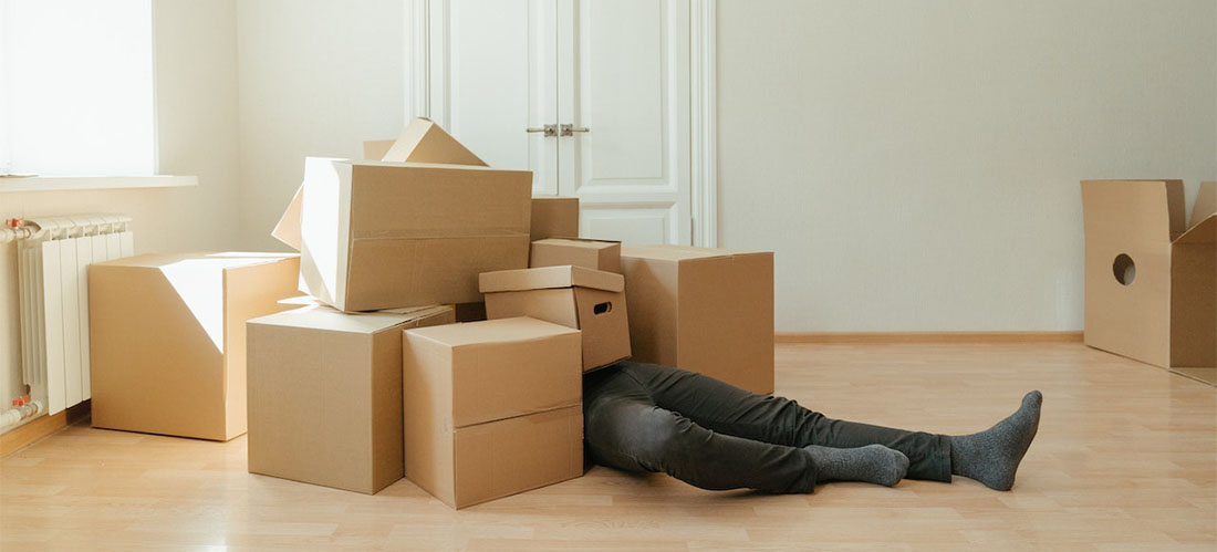 A person laying on the floor surrounded by carton boxes.