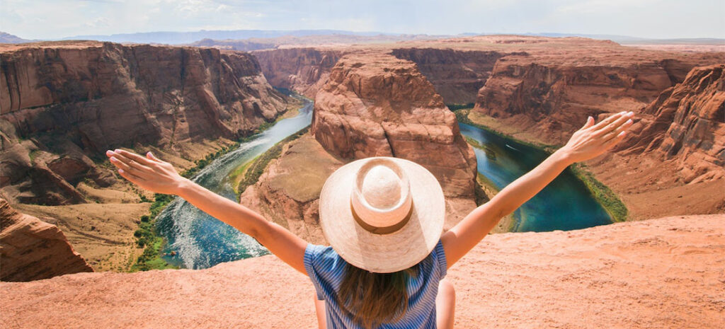 A woman holding her hands up in front of the Grand Canyon.