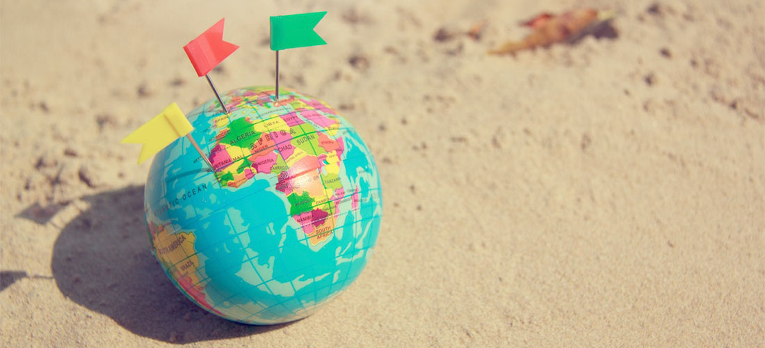 A tiny globe with flags placed on the sand