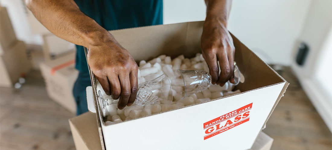 movers packing a glass into a box that's named 