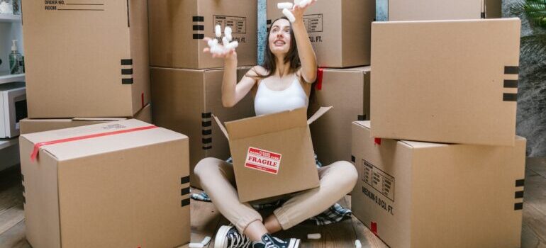 A woman sitting between packed moving boxes