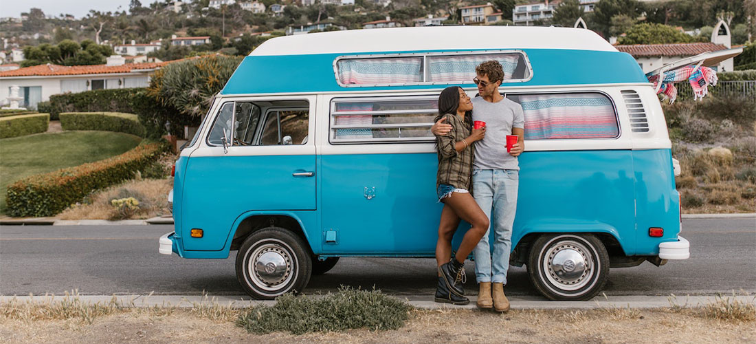 A couple standing next to a blue van.