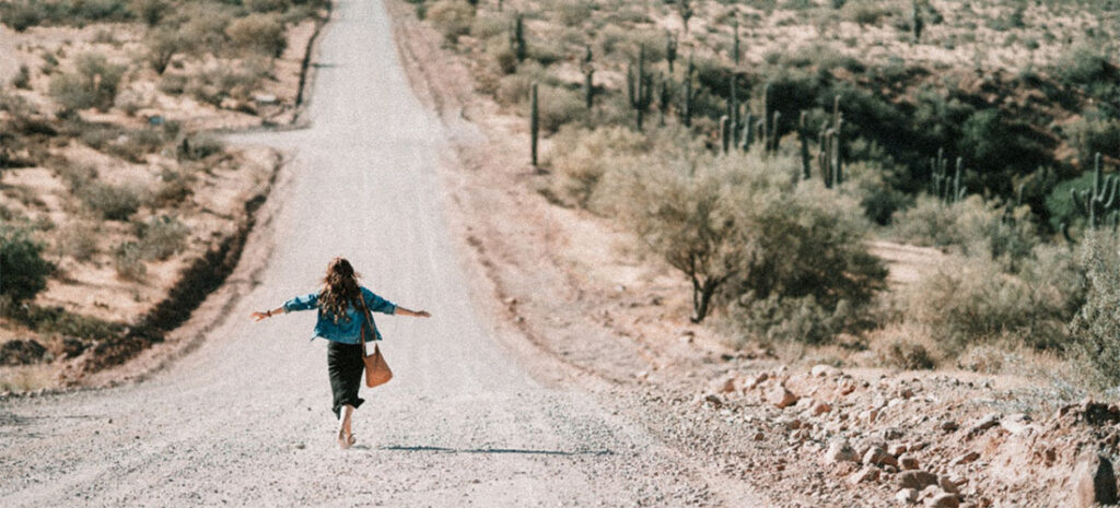 A woman walking on a dirt road thinking about hiring cross country movers Arizona offers.