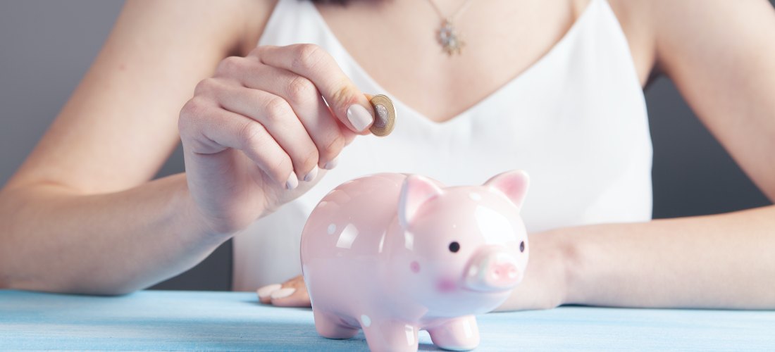 A woman putting a coin in piggy bank