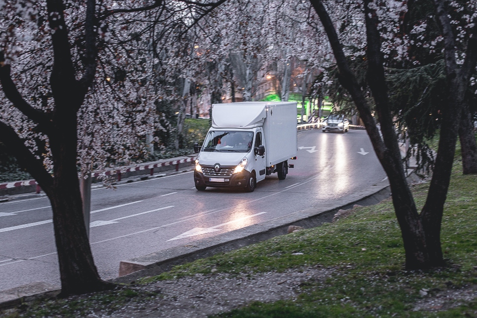 A white moving van driving on the road