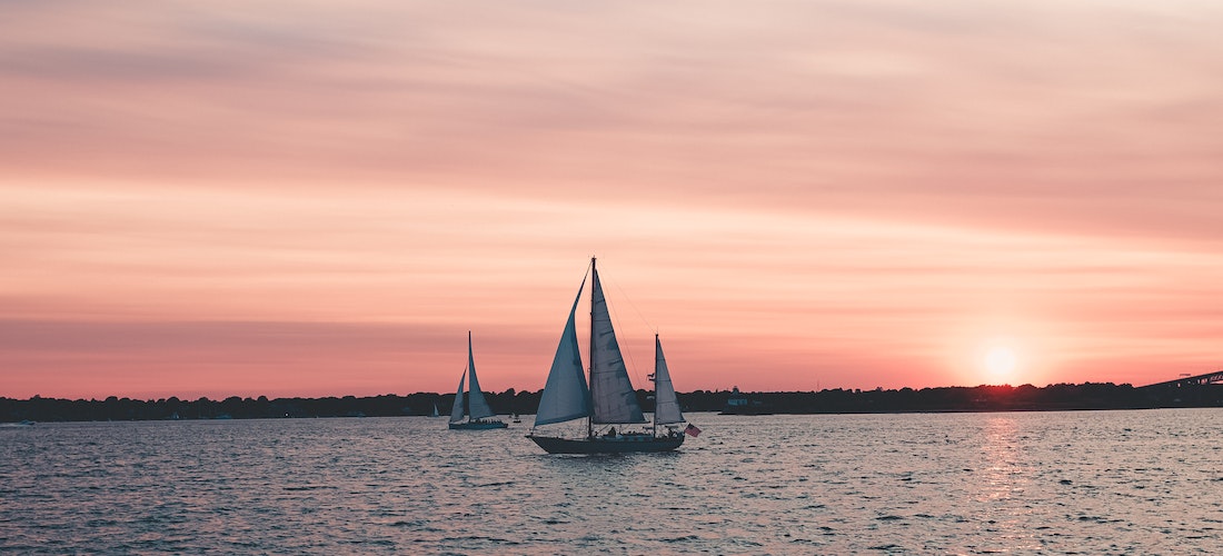 A sail boat on the sea during sunset
