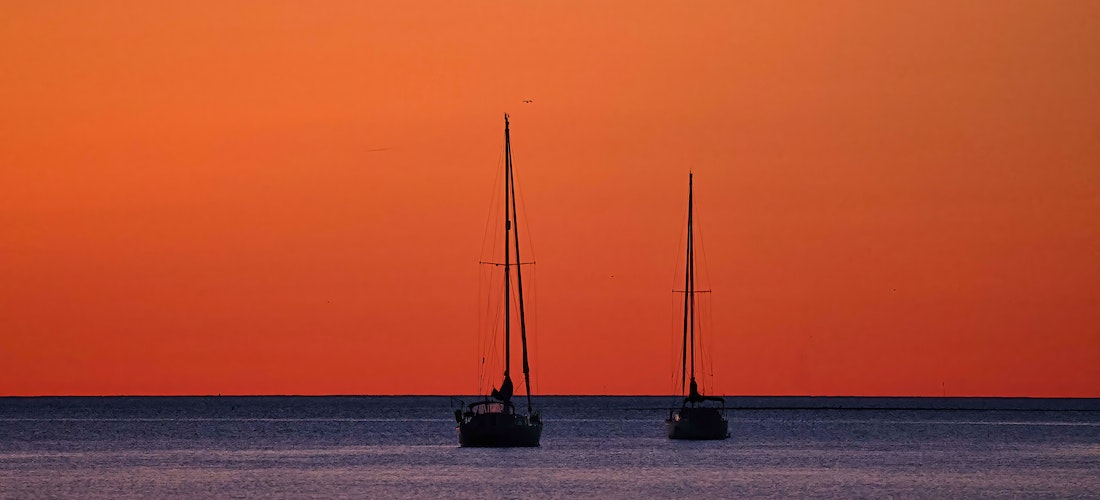 Two boats sailing under the red sky